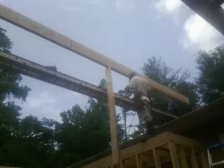 Carpenter setting a ridge beam over a new addition frame — Ice Dam Removal by Roofing Brothers in Chesapeake Beach