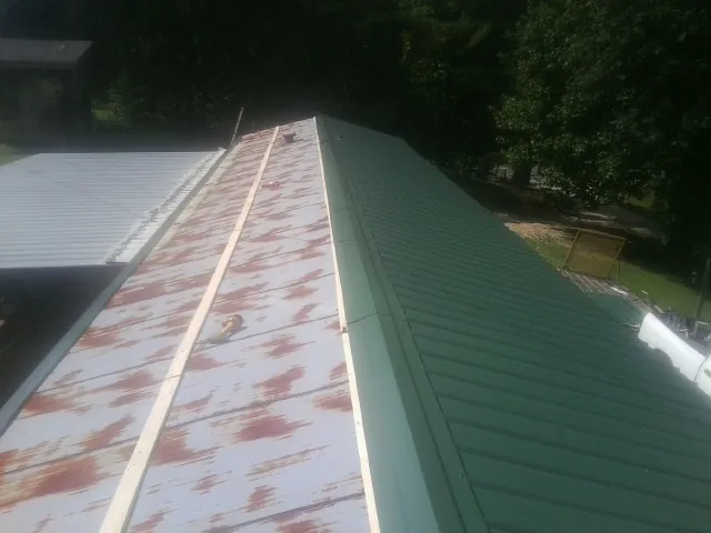 Old rusted panels beside newly installed green metal roofing — Wind Damage Roof Repair by Roofing Brothers in Chesapeake Beach
