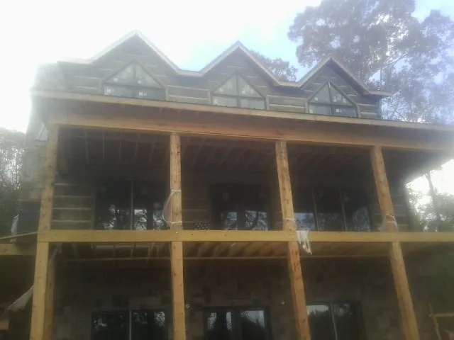 Dormers and porch framing on a large log home under construction — Roof Coating work by our crew in Chesapeake Beach