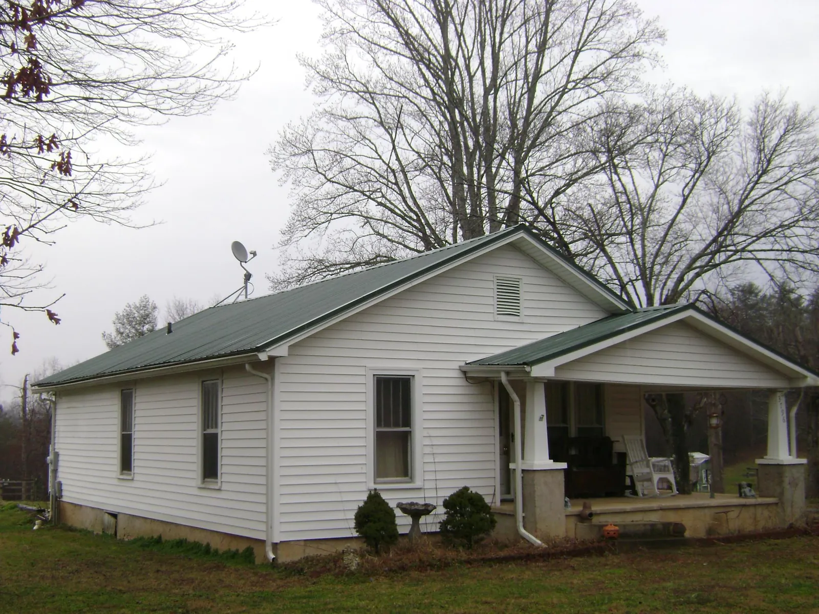 Green metal roof on a white bungalow with a side porch in Chesapeake Beach