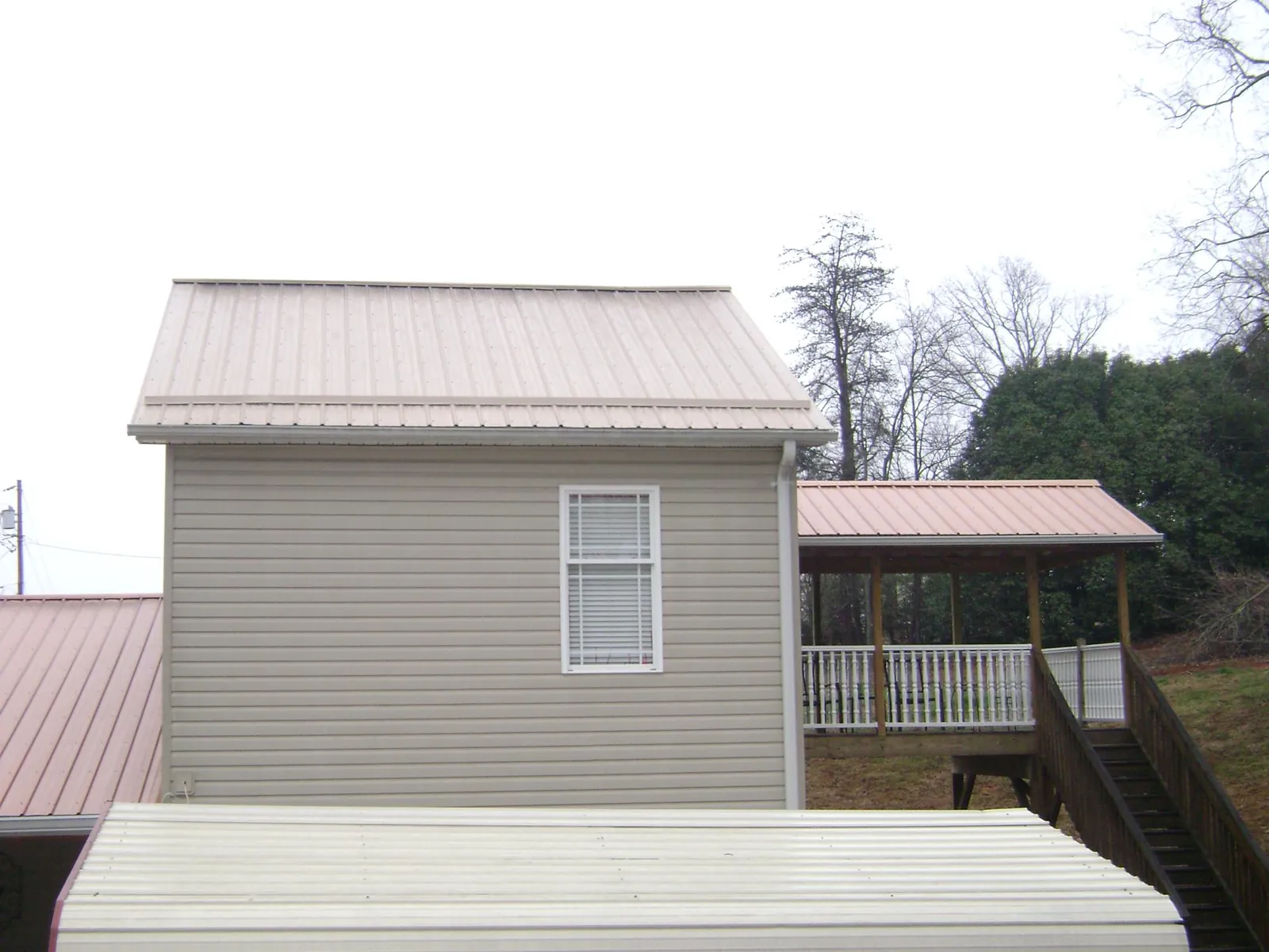 Tan metal roofs on a two story addition and attached porch, from a Roof Replacement job in Chesapeake Beach