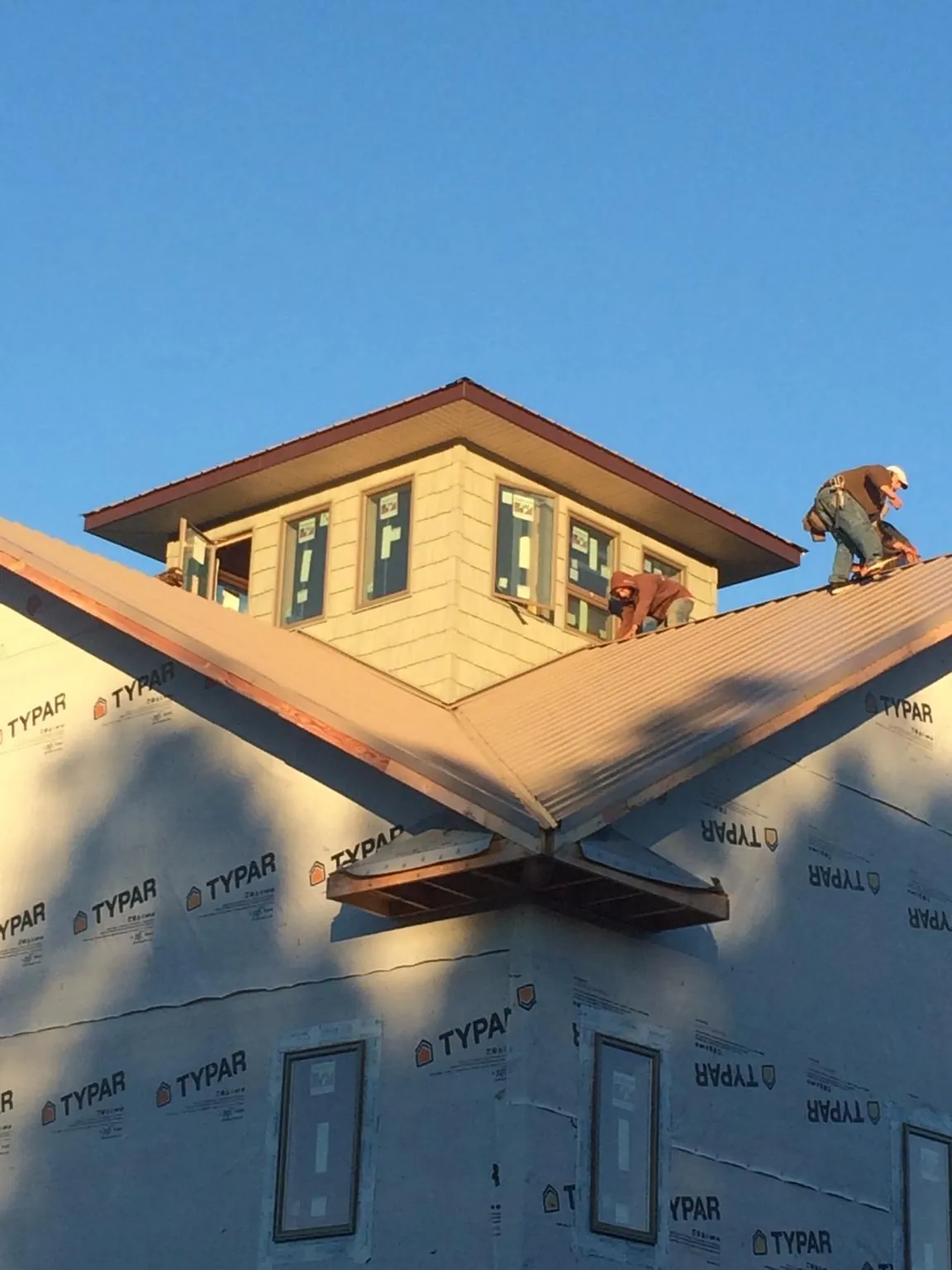 Roofers working around a rooftop cupola on a new metal roof at sunset — Roof Waterproofing in Chesapeake Beach by Roofing Brothers